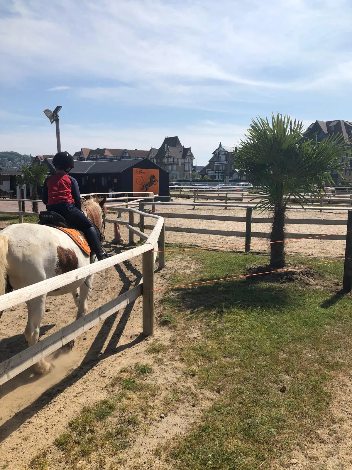 Uma criança num pónei junto às cavalariças